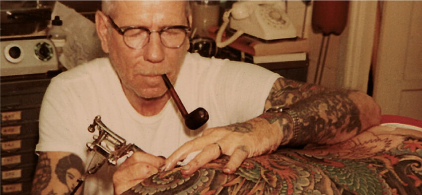 Sailor Jerry tatuando con pipa